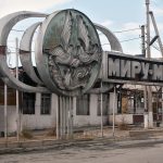 sowjetische Installation mit der Aufschrift „Frieden der Welt“ vor ausgebrannten Gebäuden des Basars in Osch